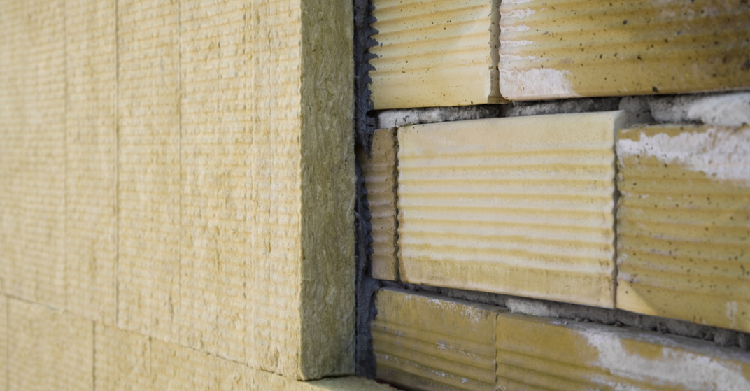 Querschnitt einer Wand aus Ziegeln mit fünf Zentimeter dicken Dämmplatten an der Außenseite für besseren U-Wert
