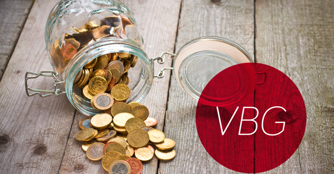 Gekipptes Einmachglas mit verschiedenen Euro- und Centmünzen liegt umgekippt auf einem rustikalen Holzboden, dazu der Text "VBG" in rotem Kreis.